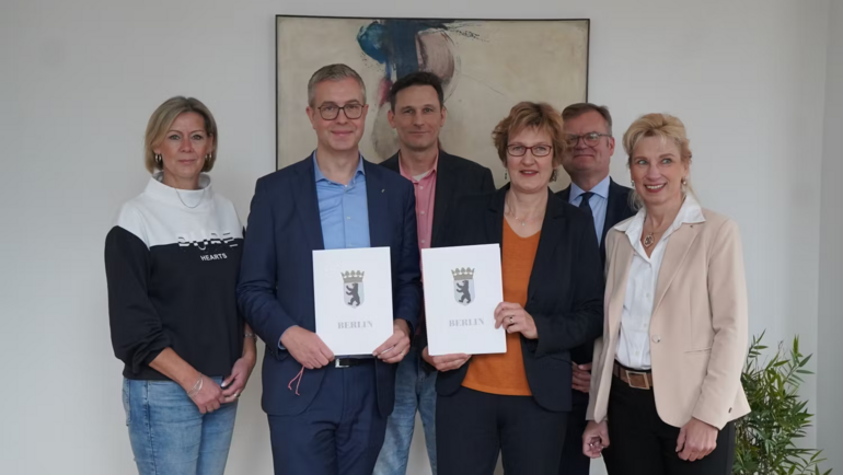 Bild zeigt Personengruppe mit einer unterzeichneten Vereinbarung