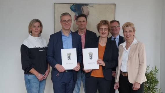 Bild zeigt Personengruppe mit einer unterzeichneten Vereinbarung